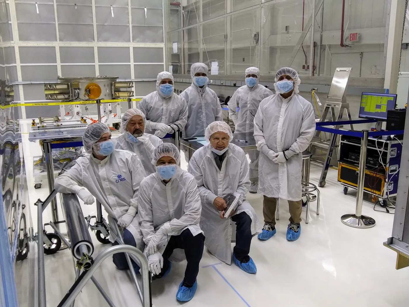 A combined customer and ALS team photographed in the cleanroom alongside an integrated payload stack.